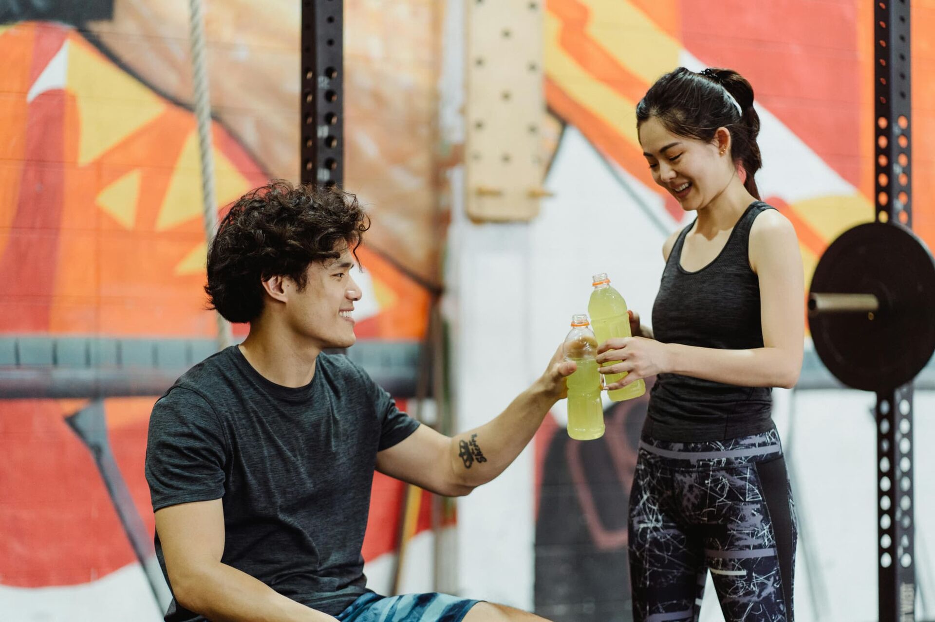 スポーツジムでペットボトルで乾杯する男女