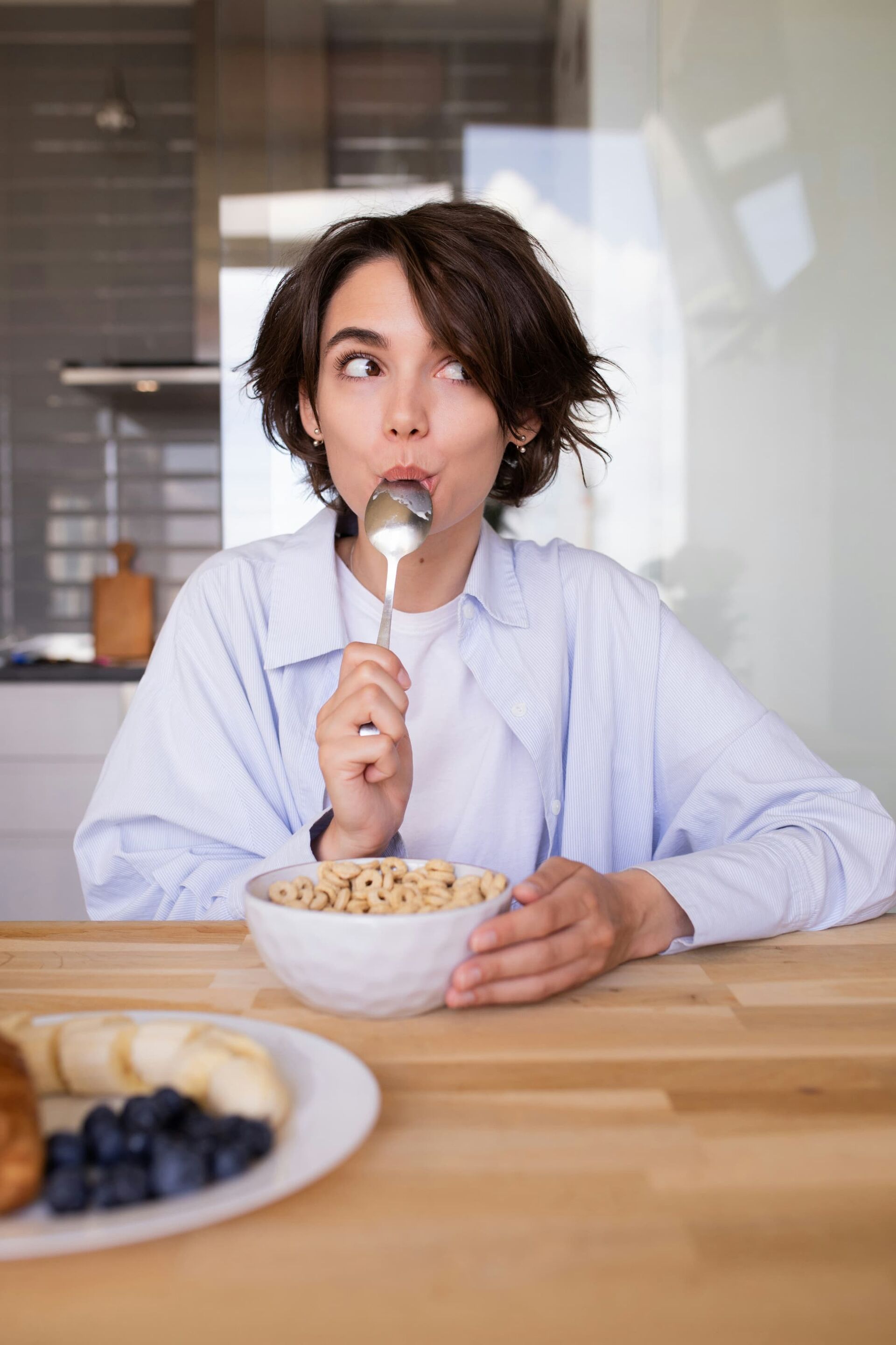 女性が朝食にフルーツとシリアルをスプーンで食べている様子